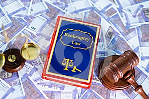 Concept of commencement of bankruptcy law, showing by placing bankruptcy law book on banknotes with judge gavel and balance scale