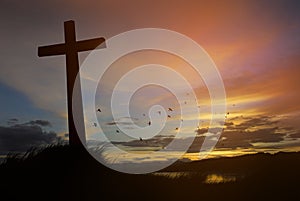 Concept conceptual black cross religion symbol silhouette in grass over sunset