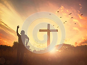 Concept conceptual black cross religion symbol silhouette in grass over sunset or sunrise sky