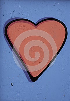 Concept or conceptual painted red abstract heart shape love symbol, vibrant blue wall background, metaphor to urban and
