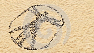 Stones on beach sand handmade symbol shape, golden sandy background, sign of vitruvius man photo