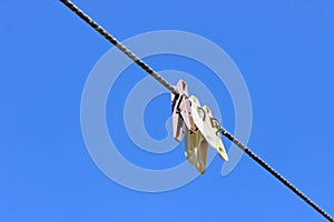 The concept of confiscation and bankruptcy. Three clothespins on a rope against the blue sky.