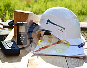 The concept of the construction of a frame house, on a wooden table made of boards lie a white helmet, goggles and other tools