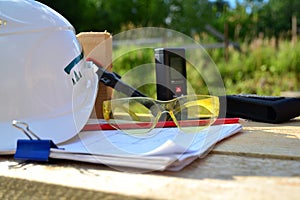 The concept of the construction of a frame house, on a wooden table made of boards lie a white helmet, goggles and other tools