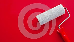 The concept of construction malar works. New clean white paint roller on a red background. Copy space