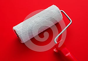 The concept of construction painting work. New clean white paint roller against red background