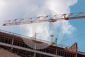 The concept of the construction process. Building under construction, with iron bars, and a crane, on blue sky background