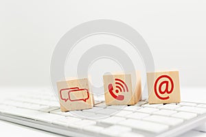 Concept of contact us. wooden cube blocks with contact icons on computer keyboard. symbol of connection, email telephone and