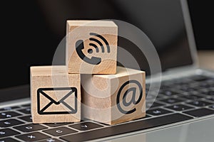 Concept of contact us. wooden cube blocks with contact icons on computer keyboard. symbol of connection, email telephone and