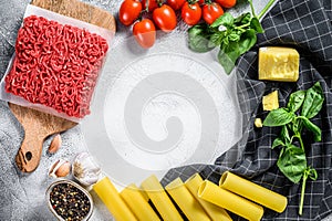 The concept of cooking cannelloni pasta with ground beef. ingredients Basil, cherry tomatoes, Parmesan, garlic. Gray background.