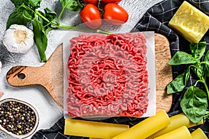 The concept of cooking cannelloni pasta with ground beef. ingredients Basil, cherry tomatoes, Parmesan, garlic. Gray background.