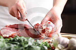 The concept of cooking meat. The chef, the butcher, cuts raw meat with beef, lamb, veal, holding a knife in his hand, on a wooden