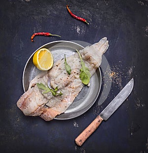 Concept cooking raw cod with herbs and lemon in a frying pan wooden rustic background top view close up