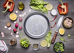 Concept cooking vegetarian food ingredients laid out around the pan with a knife spices space for text on rustic wooden backgr