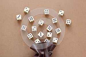 Set of white gaming dice rolled out of leather bag on brown background.