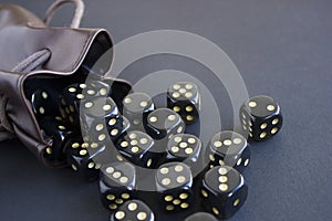 Close-up set of gaming dice rolled out of leather bag on dark background.