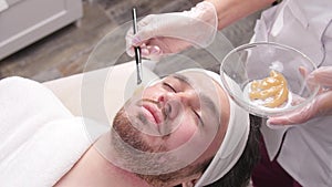 Concept of Cosmetic and spa services. Young Man with clay facial mask in beauty spa