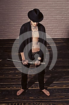 Concept of courage. Warrior in black hat and open clothes showing tattooed torso
