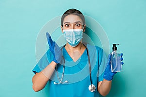 Concept of covid-19 and quarantine concept. Close-up of amazed female doctor in medical mask, gloves and scrubs, showing