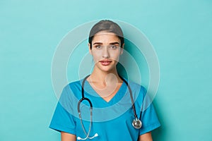 Concept of covid-19 and quarantine concept. Close-up of young confident female doctor with stethoscope, wearing scrubs