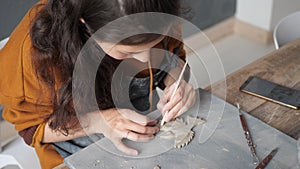 Concept of creative ceramics. Top view of potter woman hands working on details of a clay handcraft bird. Talented