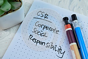 Concept of CSR - Corporate Social Responsibility write on book isolated on Wooden Table