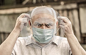 Concept danger of coronavirus for the elderly. Portrait old man in a surgical bandage, coronavirus, medical mask