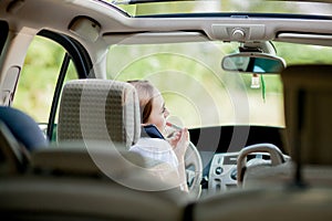 Concept of danger driving. Young woman driver red haired teenage girl painting her lips doing applying make up while driving the