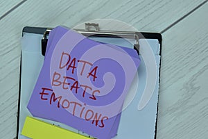 Concept of Data Beats Emotions write on sticky notes isolated on Wooden Table