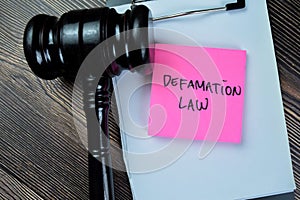 Concept of Defamation Law write on sticky notes with gavel isolated on Wooden Table