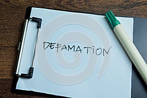 Concept of Defamation write on paperwork isolated on wooden background