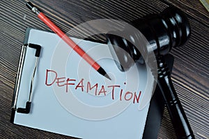 Concept of Defamation write on a paperwork isolated on Wooden Table photo