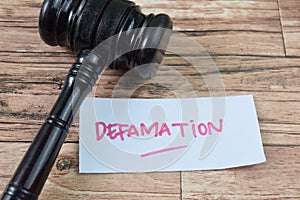 Concept of Defamation write on sticky notes isolated on Wooden Table photo