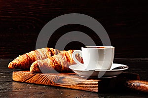 Concept of delicious breakfast, croissants and espresso on dark wooden board