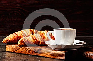 Concept of delicious breakfast, croissants and espresso on dark wooden board