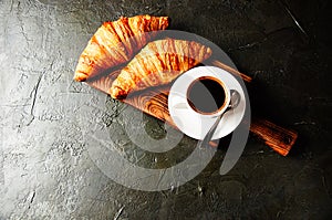 Concept of delicious breakfast, croissants and espresso on dark wooden board