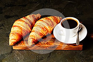 Concept of delicious breakfast, croissants and espresso on dark wooden board