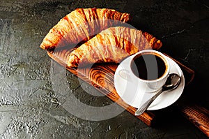 Concept of a delicious breakfast, croissants and espresso on a dark wooden board, on gray concrete, view from the top, flat lay