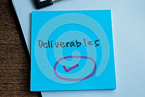 Concept of Deliverables write on sticky notes isolated on Wooden Table photo