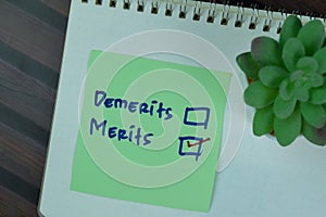 Concept of Demerits or Merits write on sticky notes isolated on Wooden Table photo