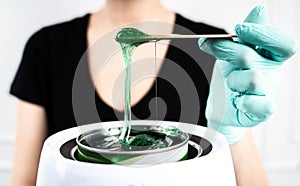 The concept of depilation and beauty is sugar paste or hair removal wax. Preparation of green wax for sugaring. Close-up