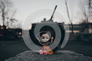 concept of destroying childhood by war. a frightened doll and tank. the concept of suffering of children and civilians