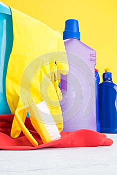 Concept of detergents and rubber gloves for cleaning on yellow background close up