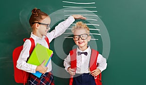 Concept of   development in education. children boy and girl students measure growth about school blackboard