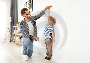 Concept of development, growing up. father measures height of his young child son photo