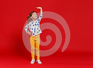 Concept of development and growth,   kid girl measuring height on  red colored background photo
