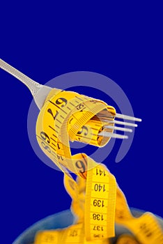 The concept of the diet. The fork rewound centimeter lying on plate closeup