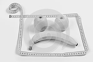Concept of diet and health. Fruit face with sad expression framed with measuring tape