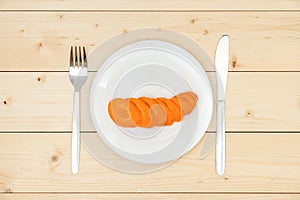 The concept of diet and healthy eating. Raw carrots cut into slices on a white plate, top view