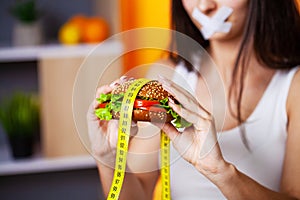 The concept of diet woman with sealed mouth keeps greasy burger